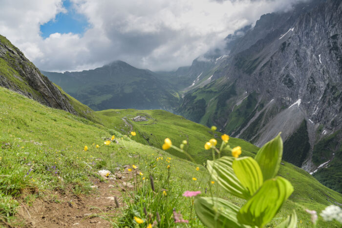 Satte grüne Wiesen und ein Bergpanorama das von dunklen Wolken getrübt wird