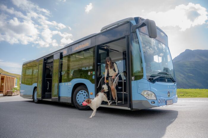 Frau steigt mit Hund an der Leine aus dem Ortsbus Lech aus.