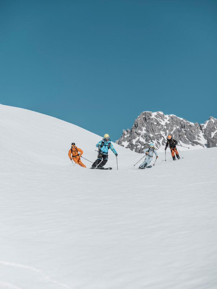 einige Skifahrer fahren über die Skipiste bei klarem blauem Himmel 