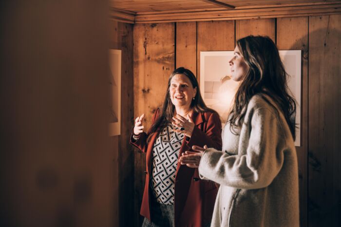 eine Dame hört gespannt bei der Führung im Lechmuseum zu, im Hintergrund sieht man ein Gemälde an einer Holzwand