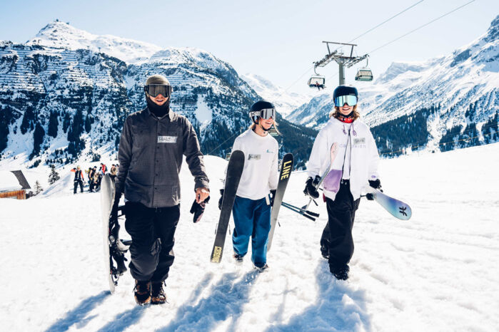 Skifahrer und Snowboarder auf der Piste in Lech vor Bergpanorama