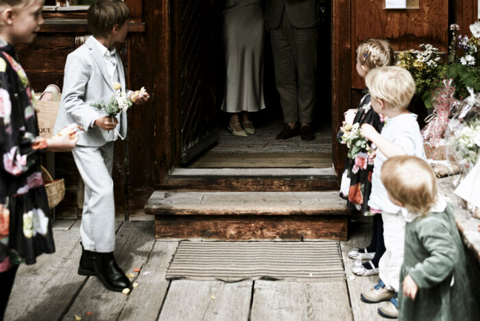 Kinder stehen vor dem Huberhus-Eingang und sind bereit die Blumen für das frisch vermählte Paar zu werfen