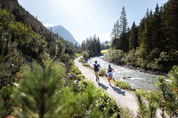 Zwei Trailrunner laufen entlang des Lech am Web nach Zug