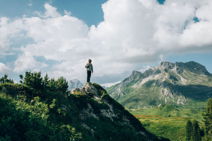 ein Wanderer steht auf einem Felsvorsprung und genießt die Aussicht auf die Gipslöcher und das traumhafte Bergpanorama im Hintergrund