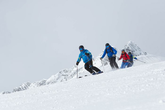 vier Skifahrer fahren über die Piste