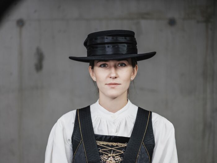 Frau in traditioneller Walsertracht mit schwarzen Hut, weißer Bluse und besticktem Kleid