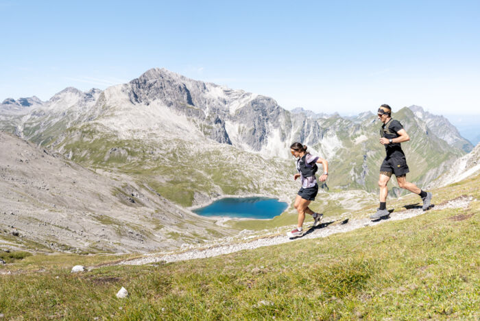 Zwei Trailrunner laufen von der Mohnenfluh runter im Hintergrund sieht man den Butzensee