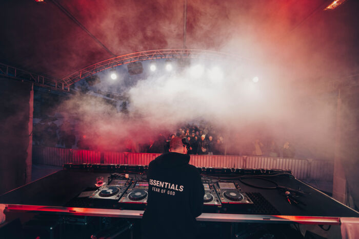 Ein DJ legt für die tanzenden und feiernden Gäste Musik auf