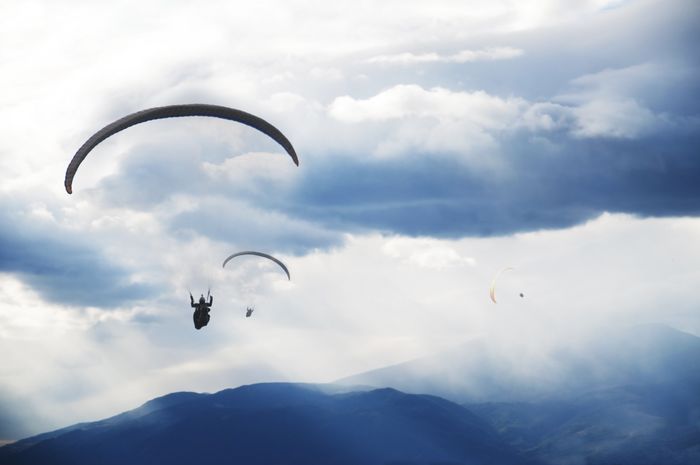 mehrere Tandemflieger fliegen durch die Wolkendecke