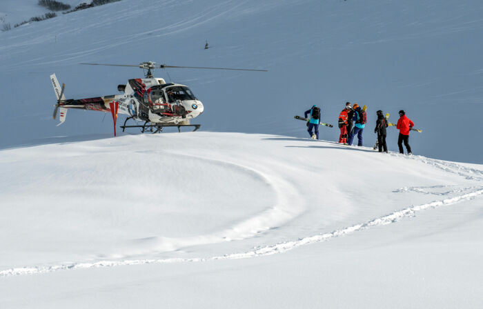 eine Gruppe von Skifahrern geht zum Hubschrauber und macht sich auf den Weg zum traumhaften Heliskiing in Lech Zürs