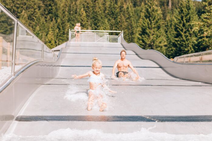 Zwei Kinder rutschen auf der Wasserrutsche