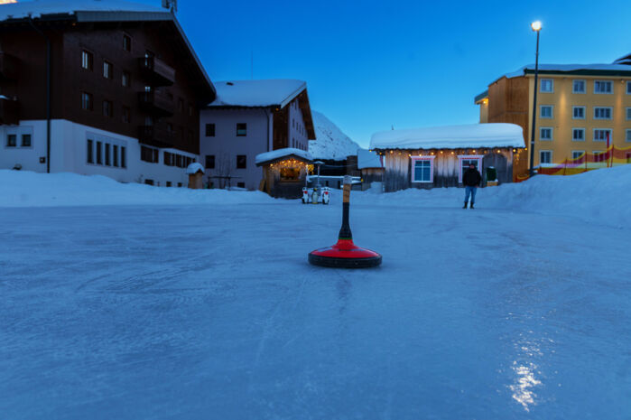 Ein Eisstock steht in der Mitte des Eislaufplatzes in Lech Zürs