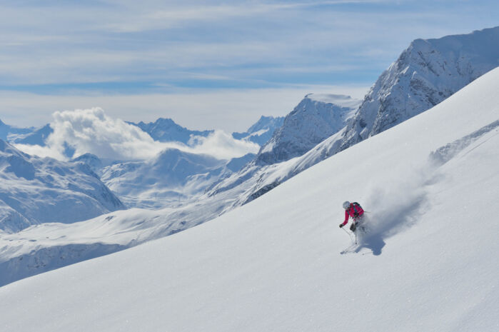 Eine Skifahrerin fährt den offenen Hang im Backcountry des Arlbergs alleine hinab