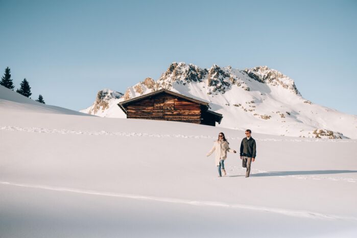 Mann und Frau beim Spazieren im Schnee vor Berg