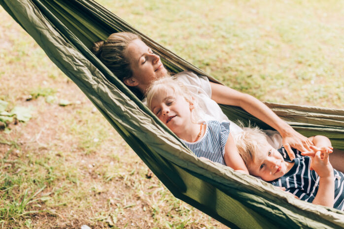 Eine Mutter beim Entspannen mit ihren Kindern in der Haengematte
