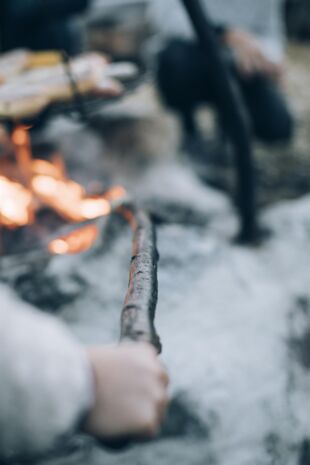 Eine Person hÃ¤lt einen Stock ins Feuer