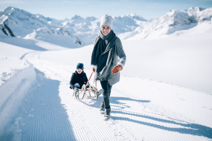 Familie beim Winterwandern mit Rodeln in Lech Zürs