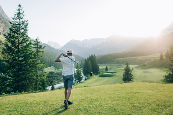 Golfer schlägt Golfball ab und blickt über den Golfplatz in Zug