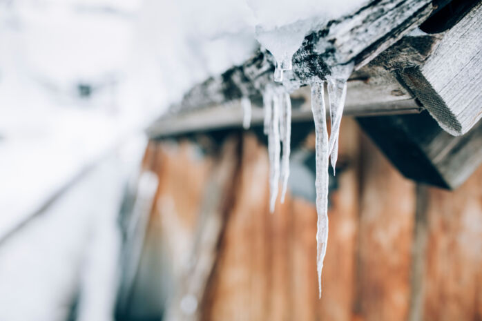 einige Eiszapfen hängen von einem schneebedeckten Holzdach