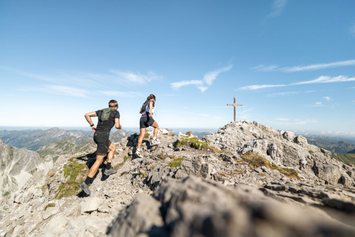 Zwei Trailrunner laufen die letzten Meter bis zum Gipfelkreuz der Mohnenfluh