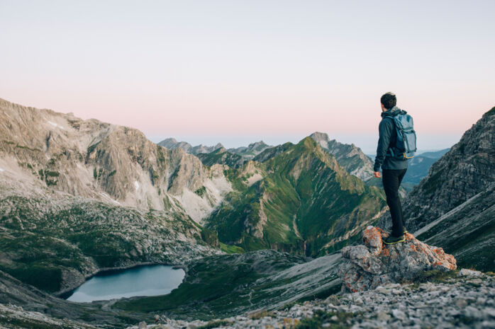 Ein Wanderer blickt hinab auf den Butzensee und genießt du Bergpanorama