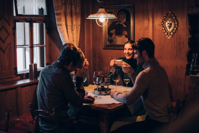 Freunde genießen gemeinsam ein gemütliches Fondue-Essen bei Wein an einem runden Tisch