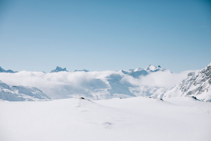 die verschneiten Berggipfel ragen aus der Wolkendecke in den klar blauen Himmel