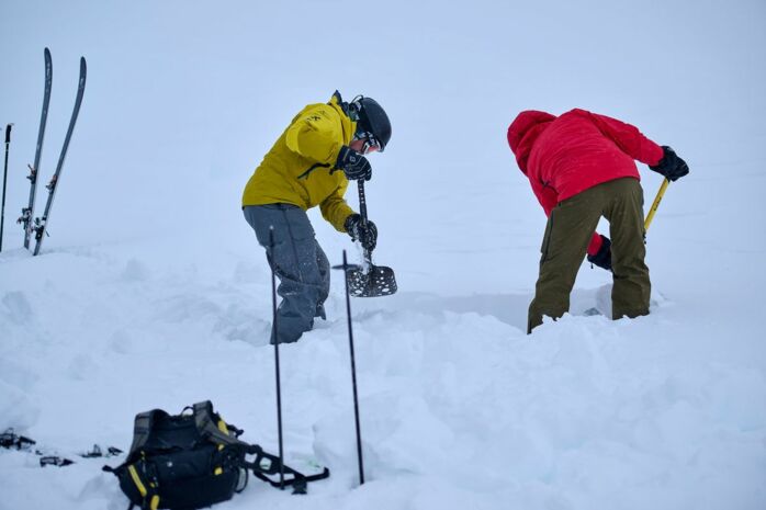 zwei Personen in Skiausrüstung schaufeln den Schnee weg, im Rahmen eines Szenarios einer Lawinenverschüttetensuche