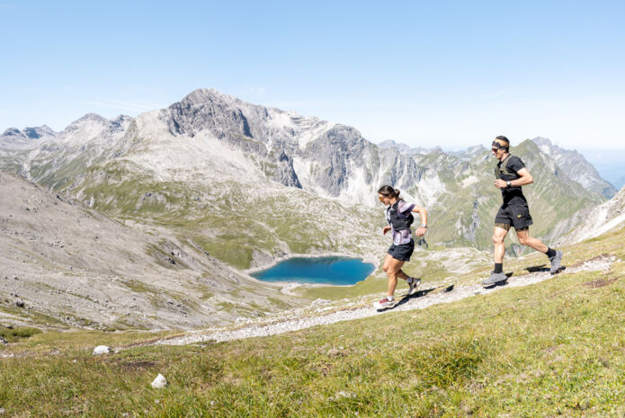 Zwei Trailrunner laufen von der Mohnenfluh runter im Hintergrund sieht man den Butzensee