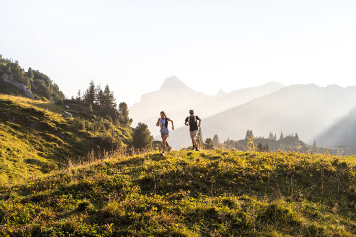 Zwei Trailrunner laufen durch die Berglandschaft von Lech 