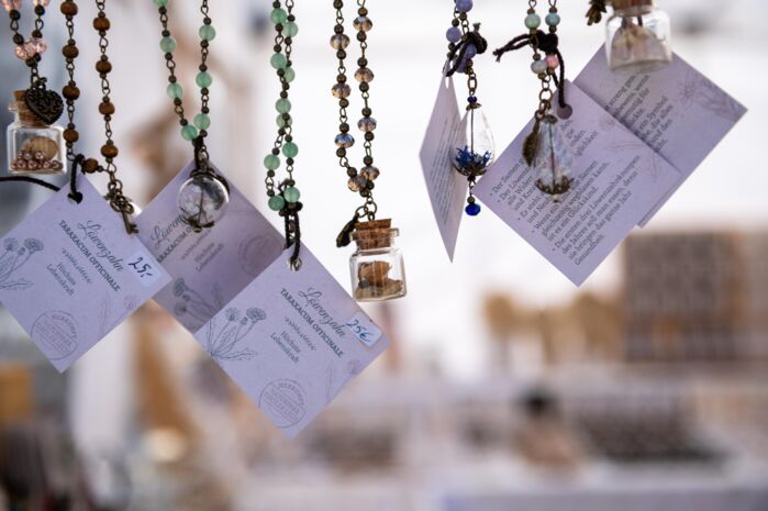 Hängende, selbstgemachte Schmuckketten und Anhänger an einem Marktstand.
