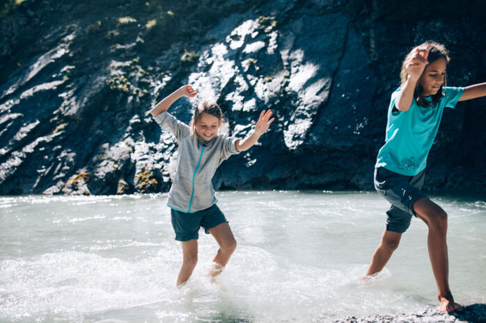 Zwei Kinder toben barfuss im Lech im Sommer