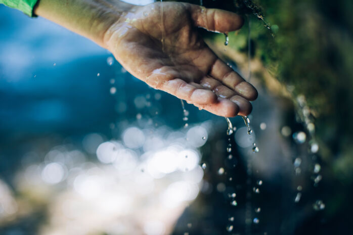ein Mann hält seine Hand unter das plätschernde Wasser vom Wasserfall in Zug