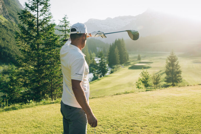 Golfer hält die Hand gegen die Sonne und blickt in die Ferne