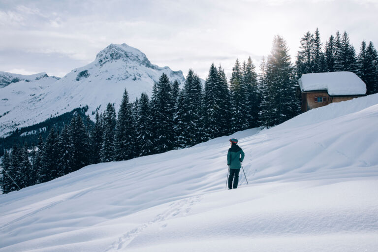 eine Skifahrerin genießt die traumhafte Aussicht auf das winterliche Bergpanorama im Sonnenschein