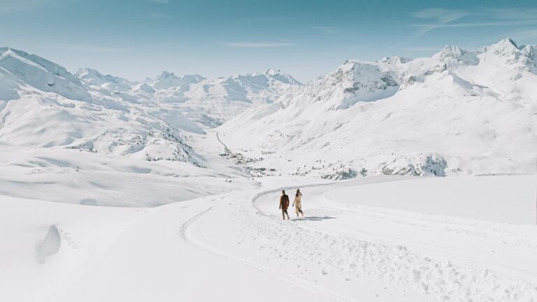 Blick auf den Schneeflockenpanoramaweg am Rüfikopf während zwei Personen gemütlich auf dem Winterwanderweg spazieren