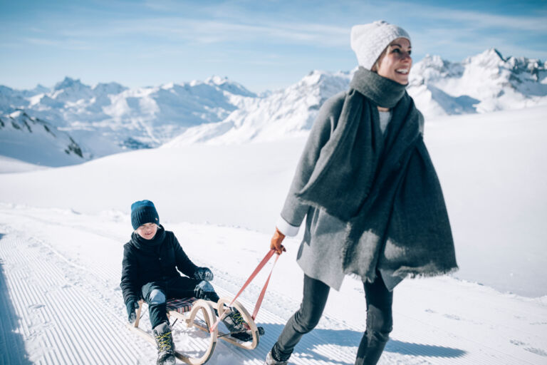 Winterwandern mit der Familie am Wanderweg Richtung Rüfikopf mit Schlitten durch die idyllisch verschneite Berglandschaft in Vorarlberg