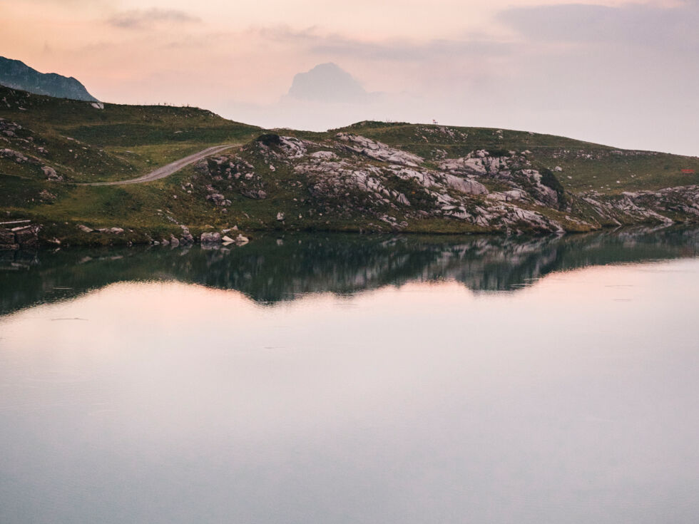 Wanderer geht entlang des Zürser Sees bei Dämmerung