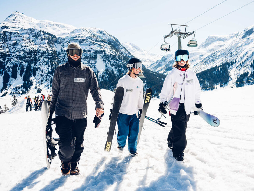 Skifahrer und Snowboarder auf der Piste in Lech vor Bergpanorama