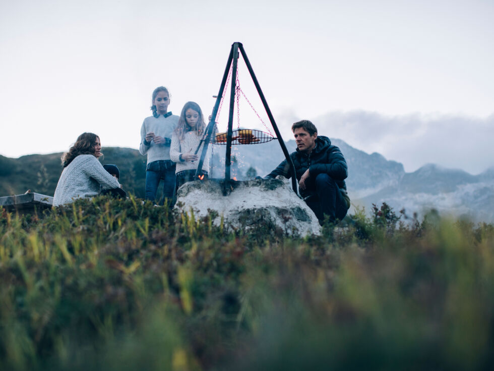 inmitten der herbstlichen Berglandschaft grillt eine Familie gemeinsam am öffentlich Grillplatz