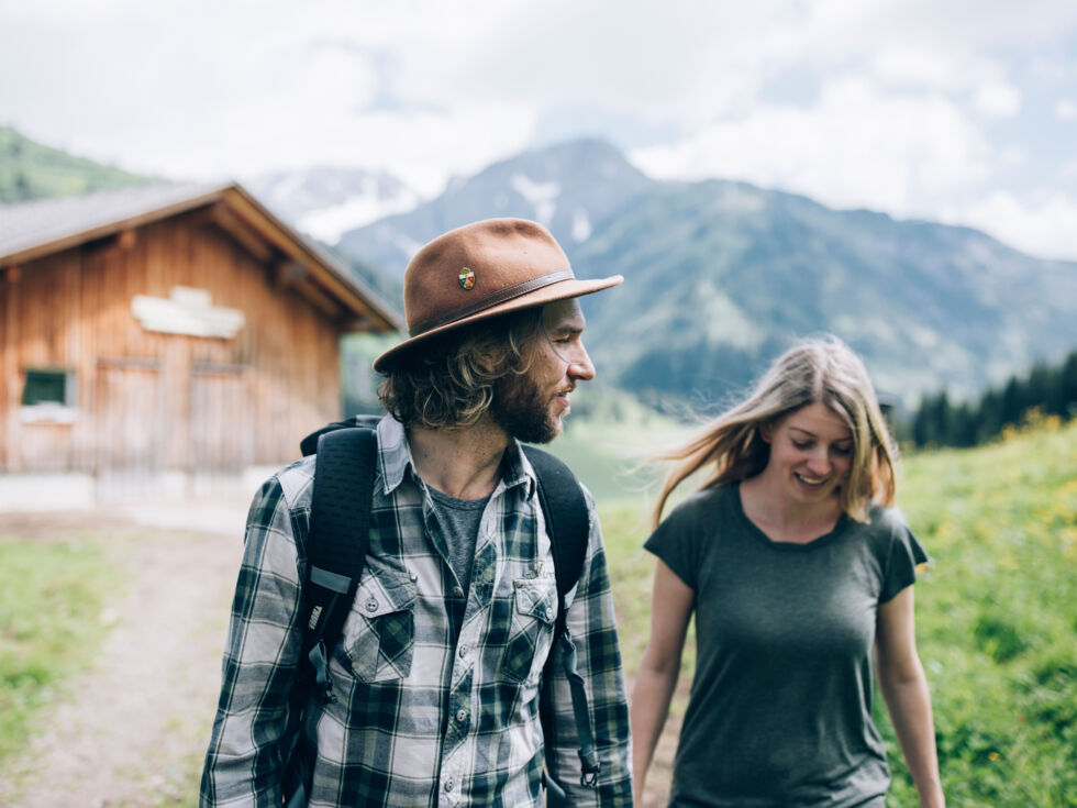 ein junges Paar wandert über den Forstweg in Bürstegg, im Hintergrund sieht man das herrliche Bergpanorama