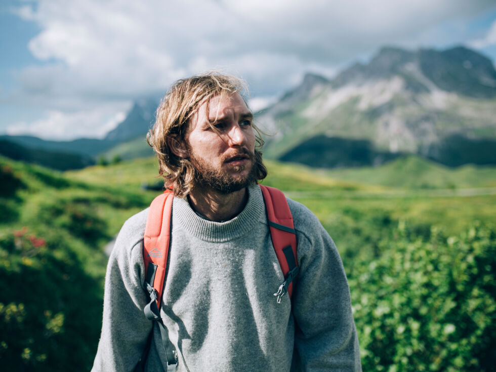 ein Mann wandert durch die weiten grünen Bergwiesen in Oberlech mit einem traumhaften Bergpanorama im Hintergrund